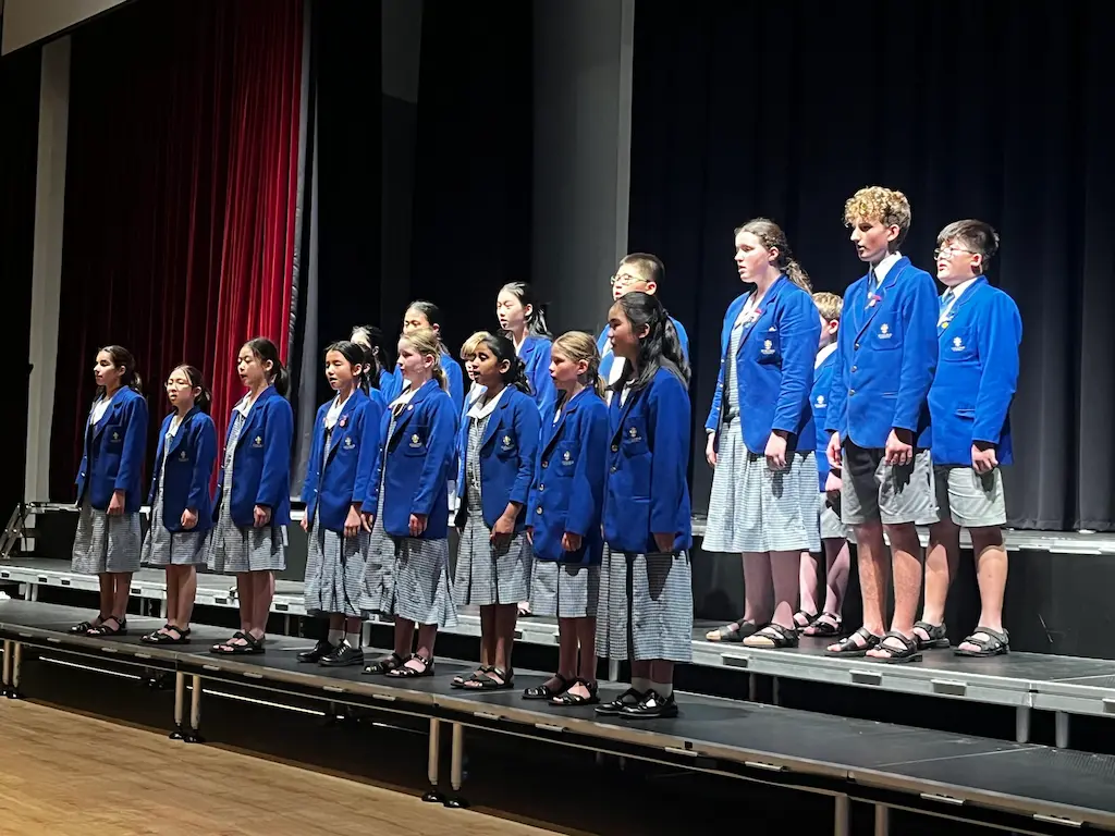 children singing on stage with information about the ficino school choir history