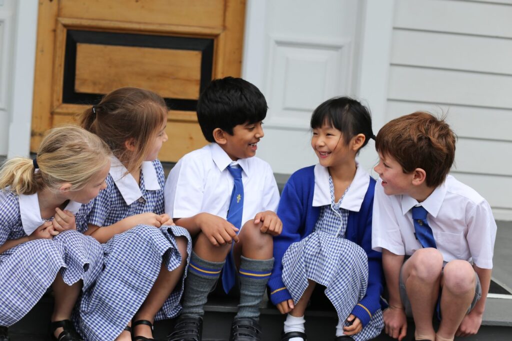 Group of young children sitting on steps outside an old villa in Auckland