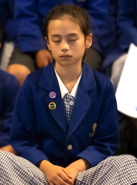 Young girls in blue school blazer practicing mindfulness.