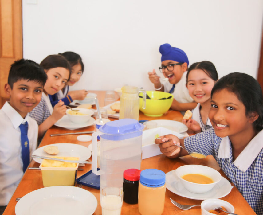 A group of young school students enjoying lunch in the dining hall together