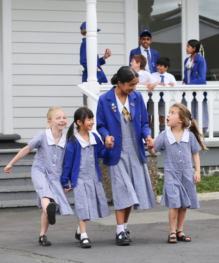 An intermediate school girl, holding hands with a group of younger girls.