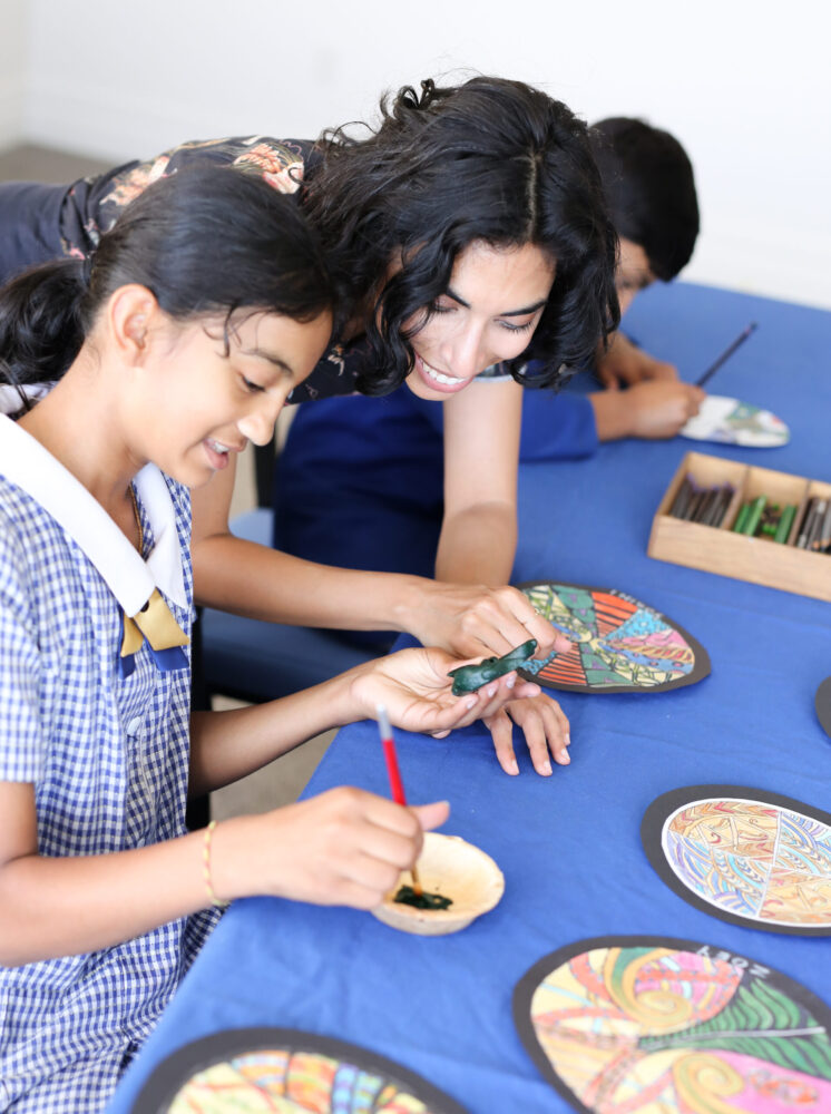 Female teacher helping young intermediate school student with her artwork