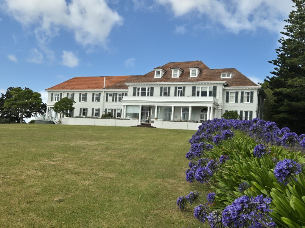 a large white house with a lawn and purple flowers