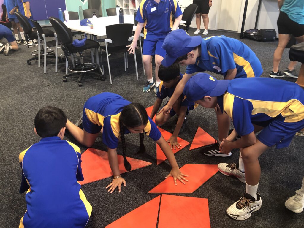 a group of kids in blue uniforms on a floor with orange squares