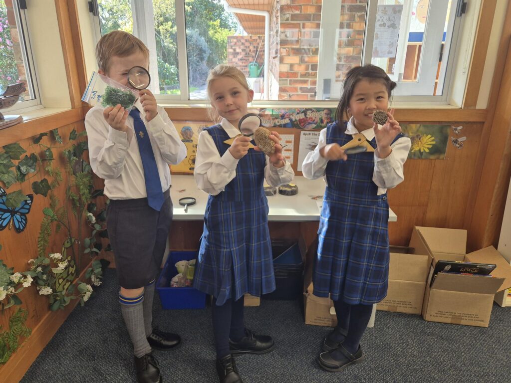 Girls and boy holding science items