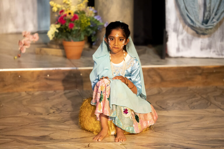 a girl sitting on a floor wearing Indian costume