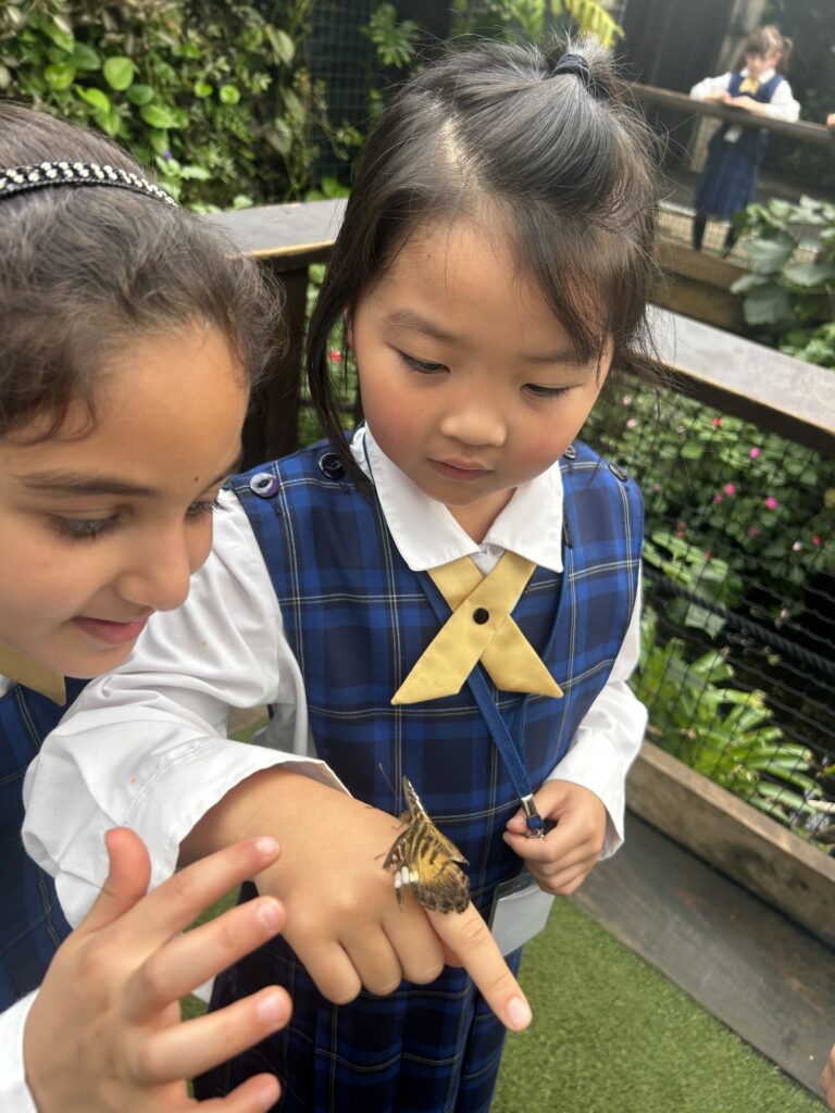 two girls look at a butterfly