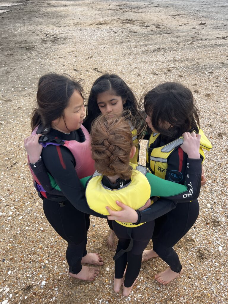 a group of girls wearing life jackets on a beach