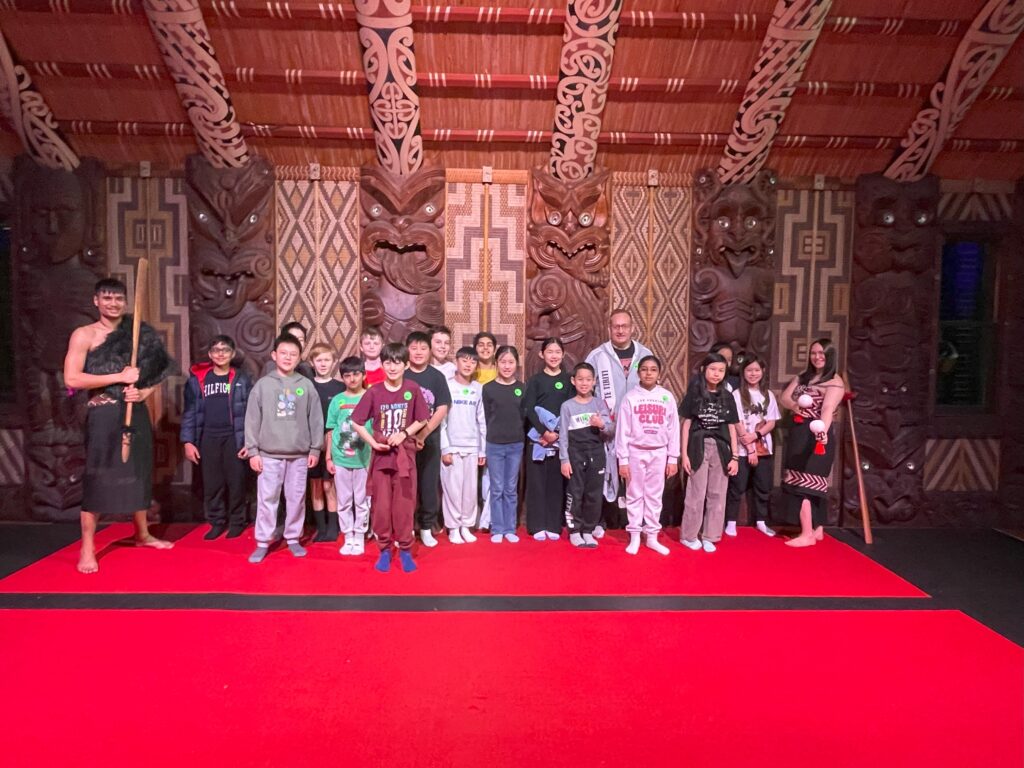 Young children pose with Maori performers in the meeting house at Waitangi