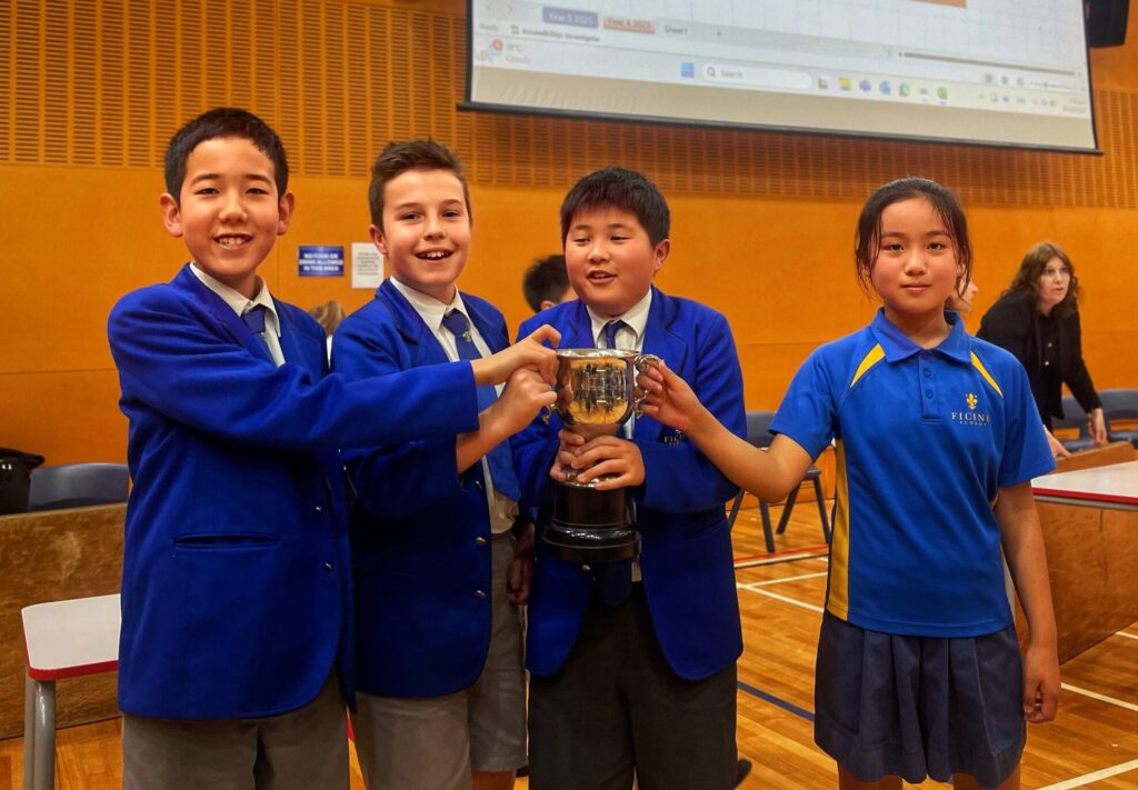 a group of kids in school uniforms holding a trophy