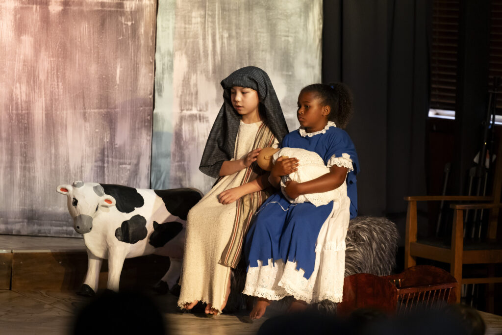 Chidren dressed as Mary and Joseph holding the baby Jesus.