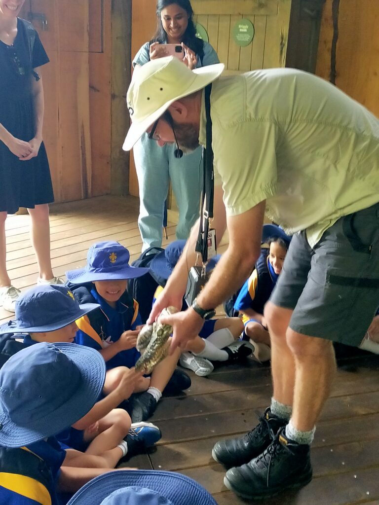 A man bending down and showing an animal skull to a group of school children
