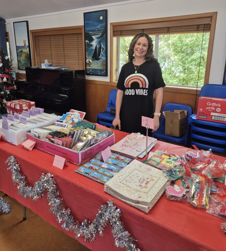 A woman standing behind a table with a red cloth