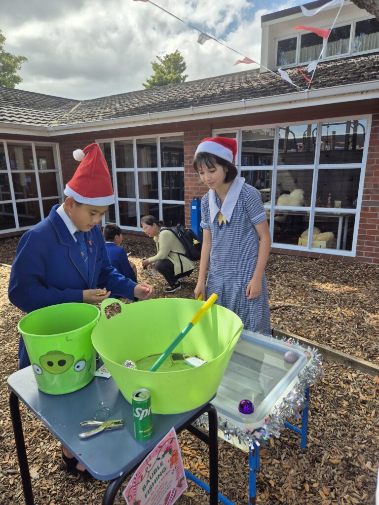Two school children standing by large green buckets