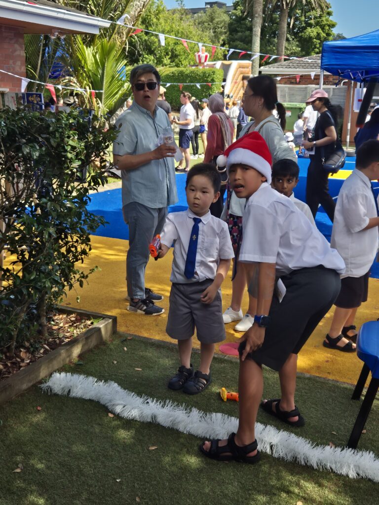 A boy wearing a santa hat plying with a younger boy