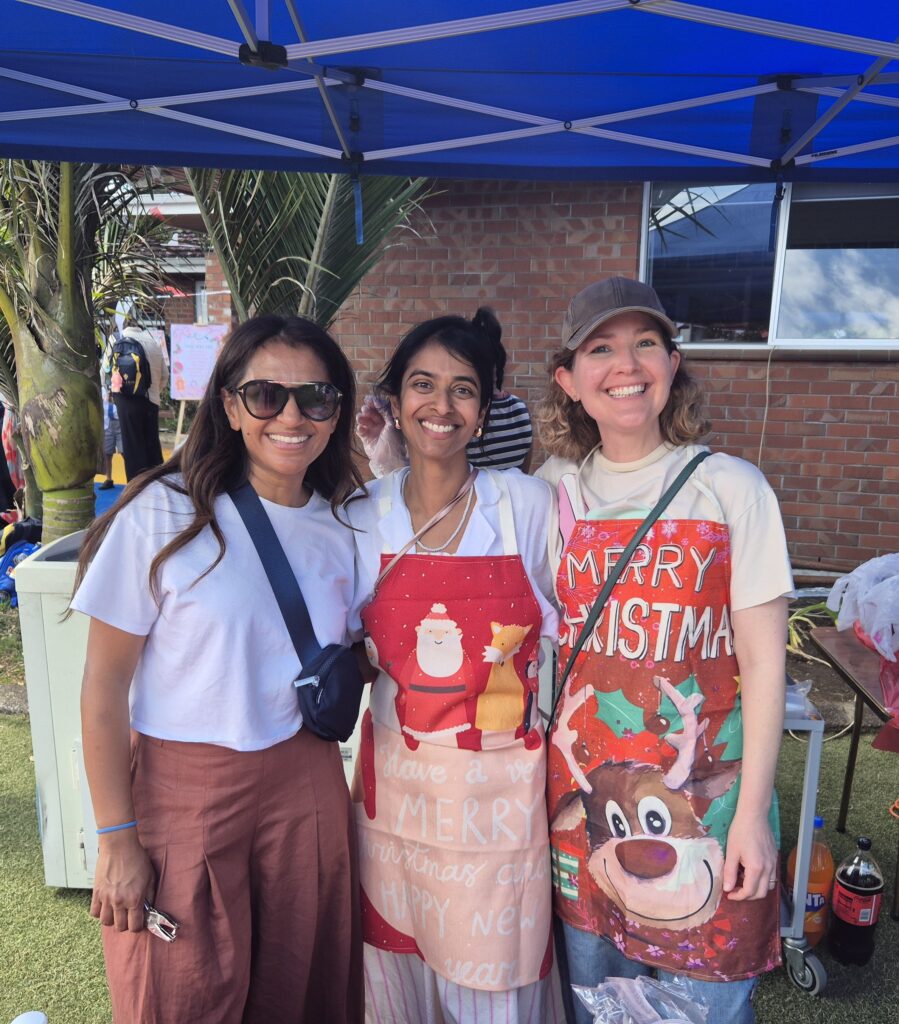 Three women wearing aprons smiling for the camera