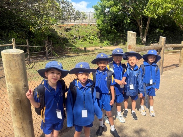 A group pf schol children wearing blue shirts and sunhats