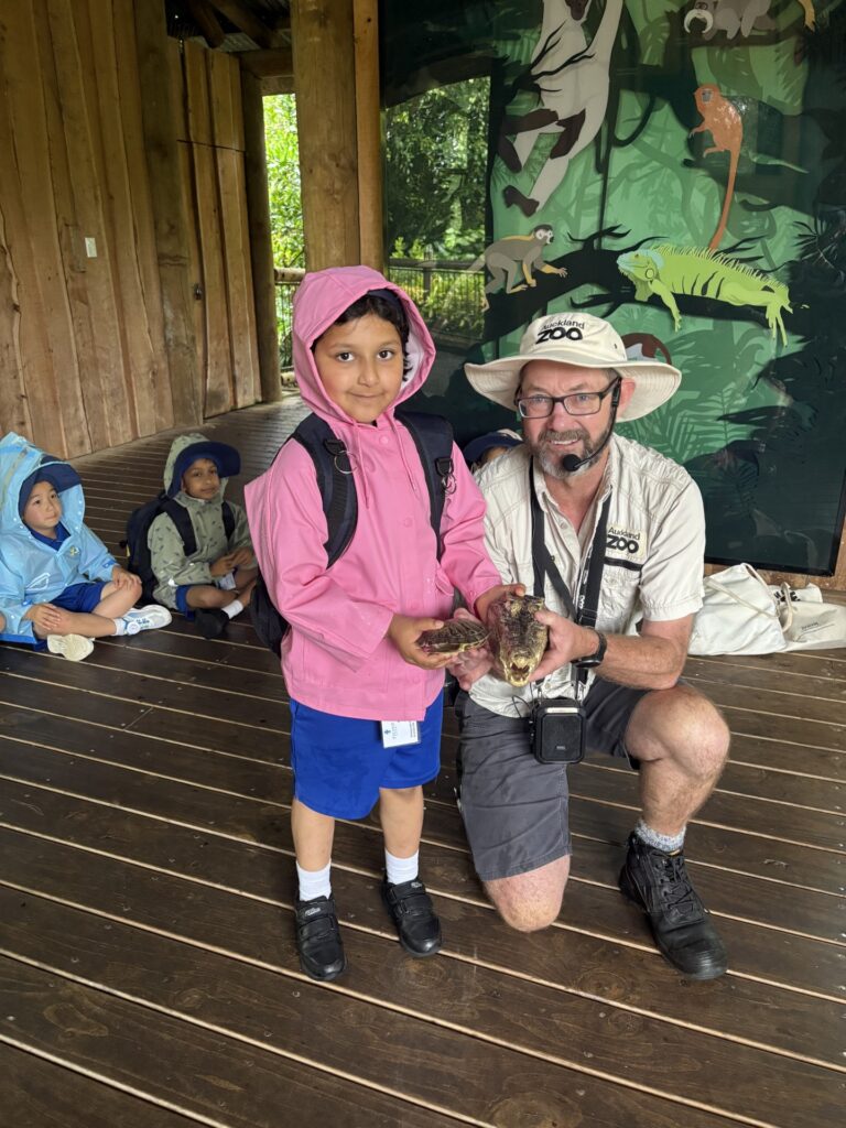 A young girls standing next to a male zoo worker