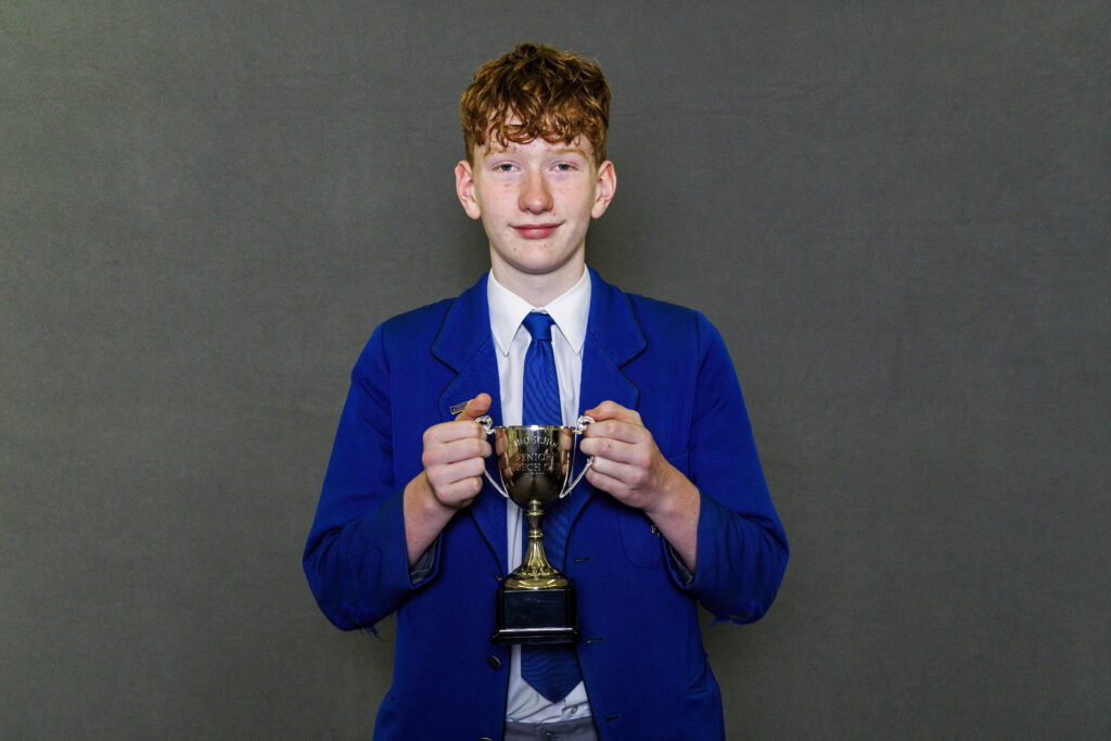 Boy in blue blazer holidng a trophy