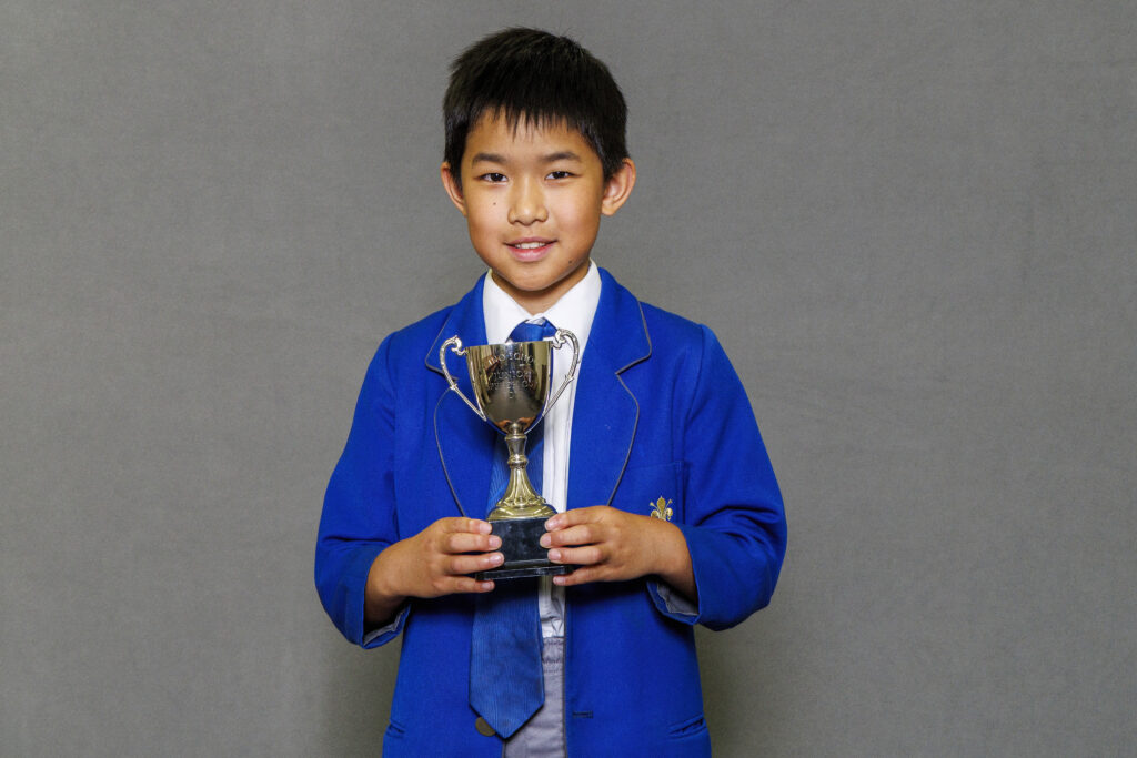 Boy in blue blazer holidng a trophy