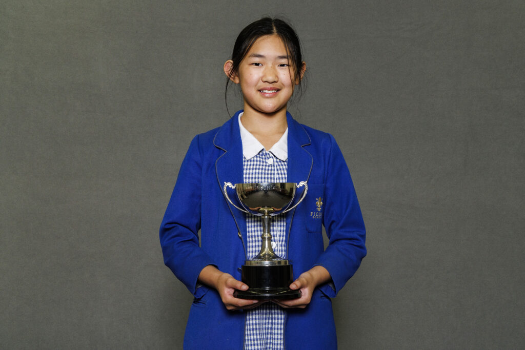 Girl in blue blazer holidng a trophy
