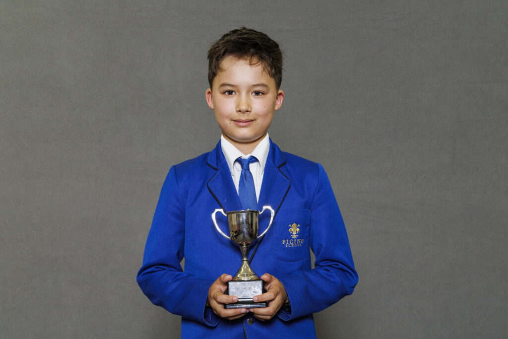 Boy in blue blazer holidng a trophy
