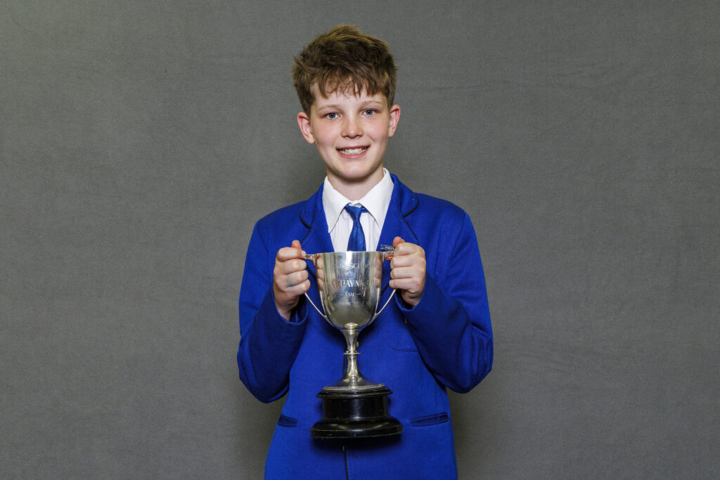 Boy in blue blazer holidng a trophy