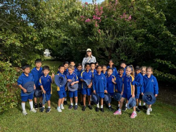 A group pf primary school children wearing blue uniforms standing in a garden