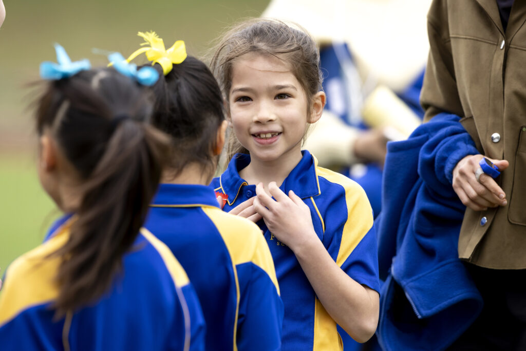 Young girl in school uniform standing in a crowd smiling