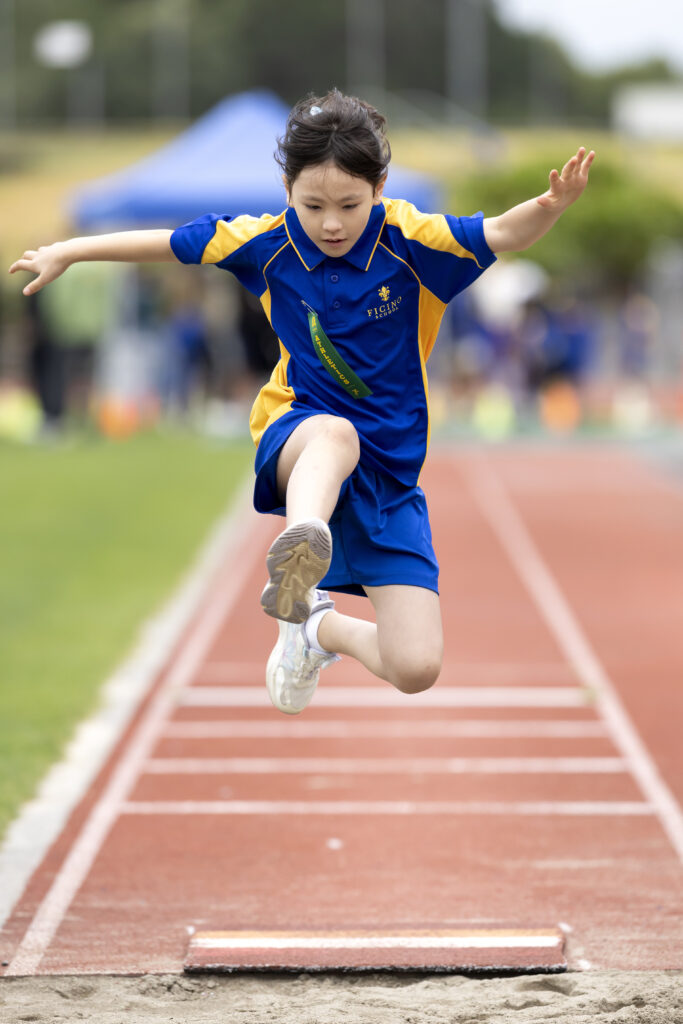 School girl doing long jump