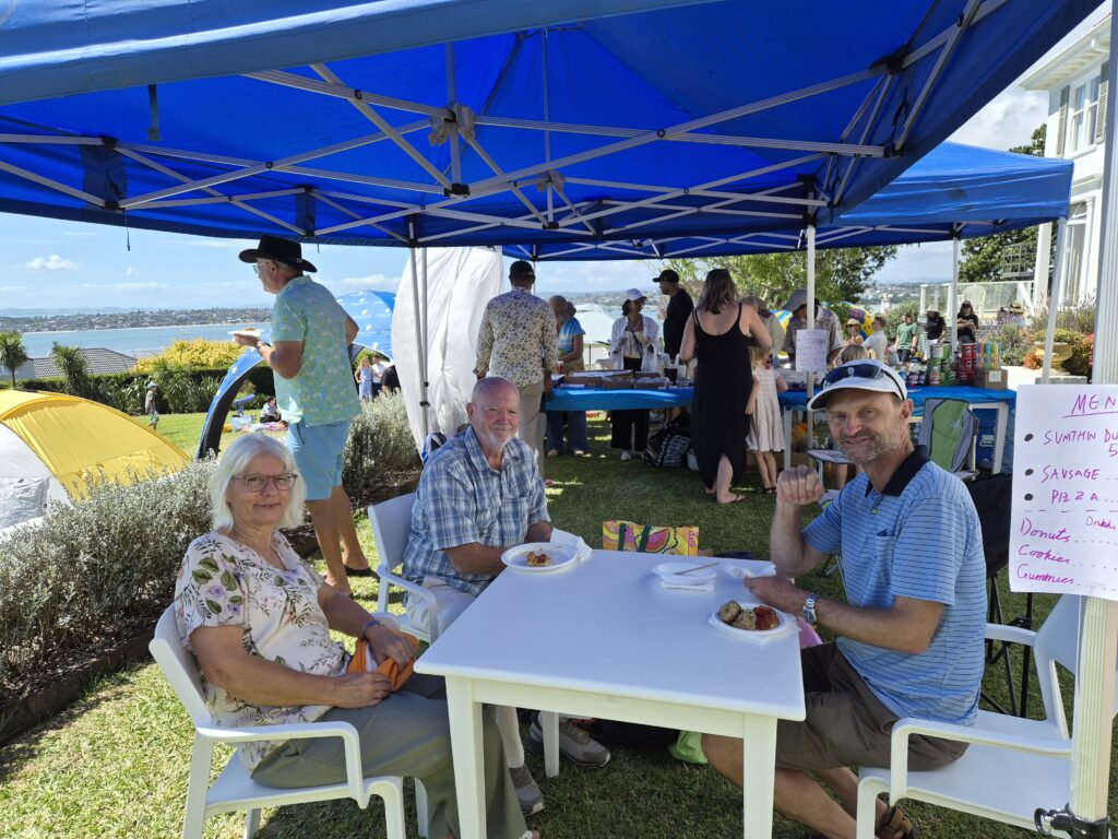 People sitting eating under a blue gazebo