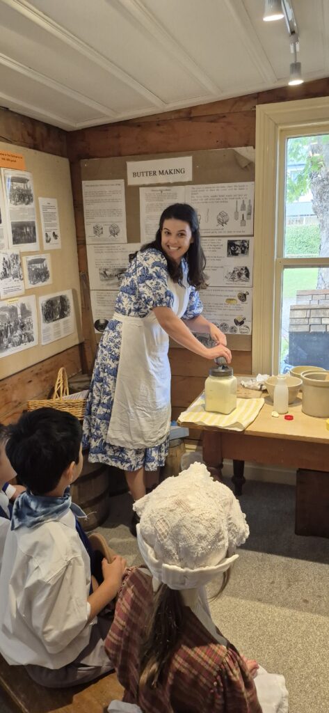 A woman in Victorian dress churning butter