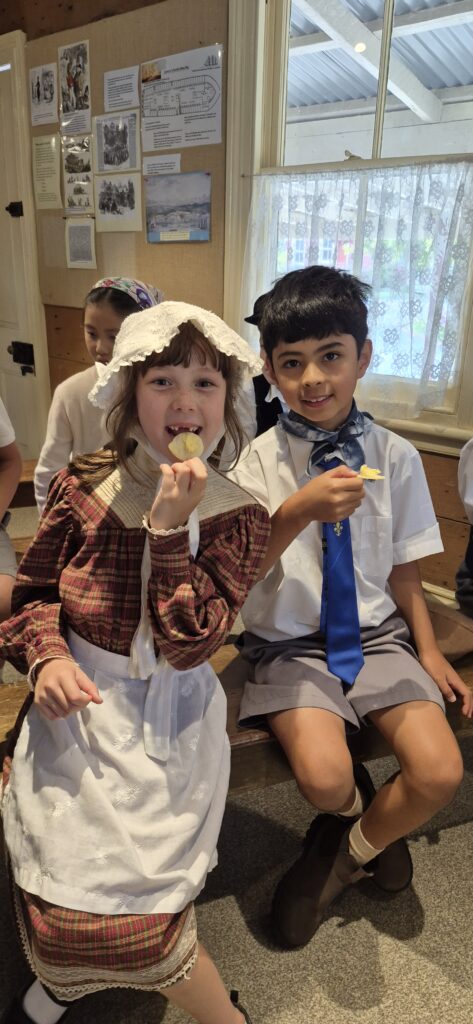 Chidren in Victorian dress eating chips