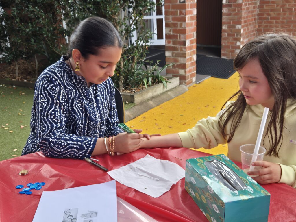 A girl doing painting her friend's hand with henna