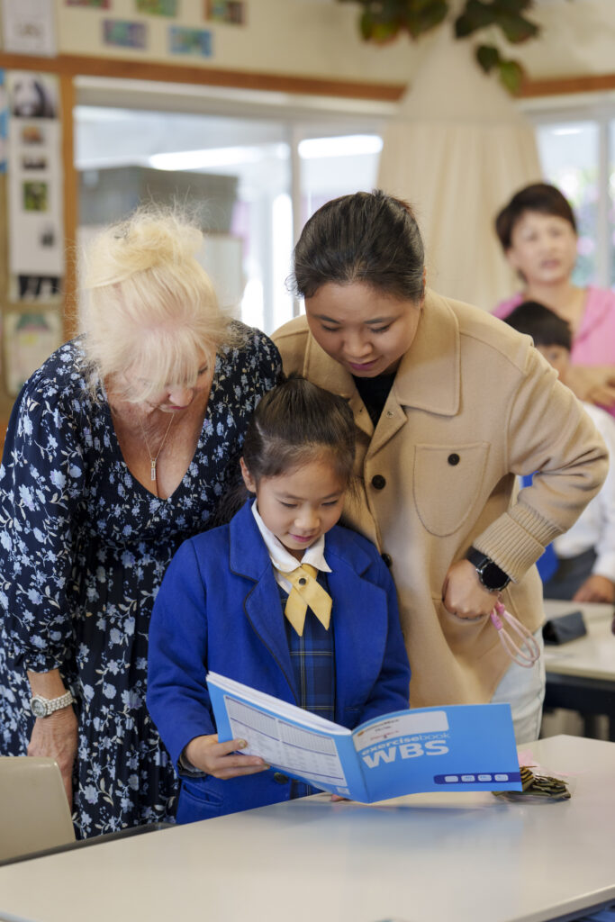 Two women looking at child's schoolbook.
