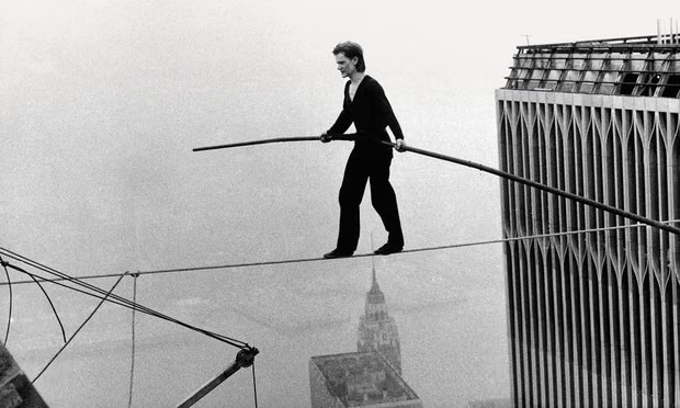 Black and white image of a man balancing on a high wire