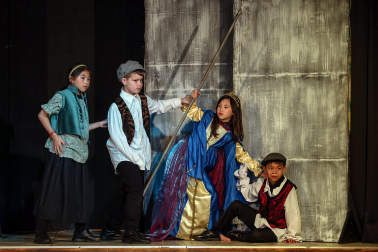 A group of students on stage perfoming in historical costume